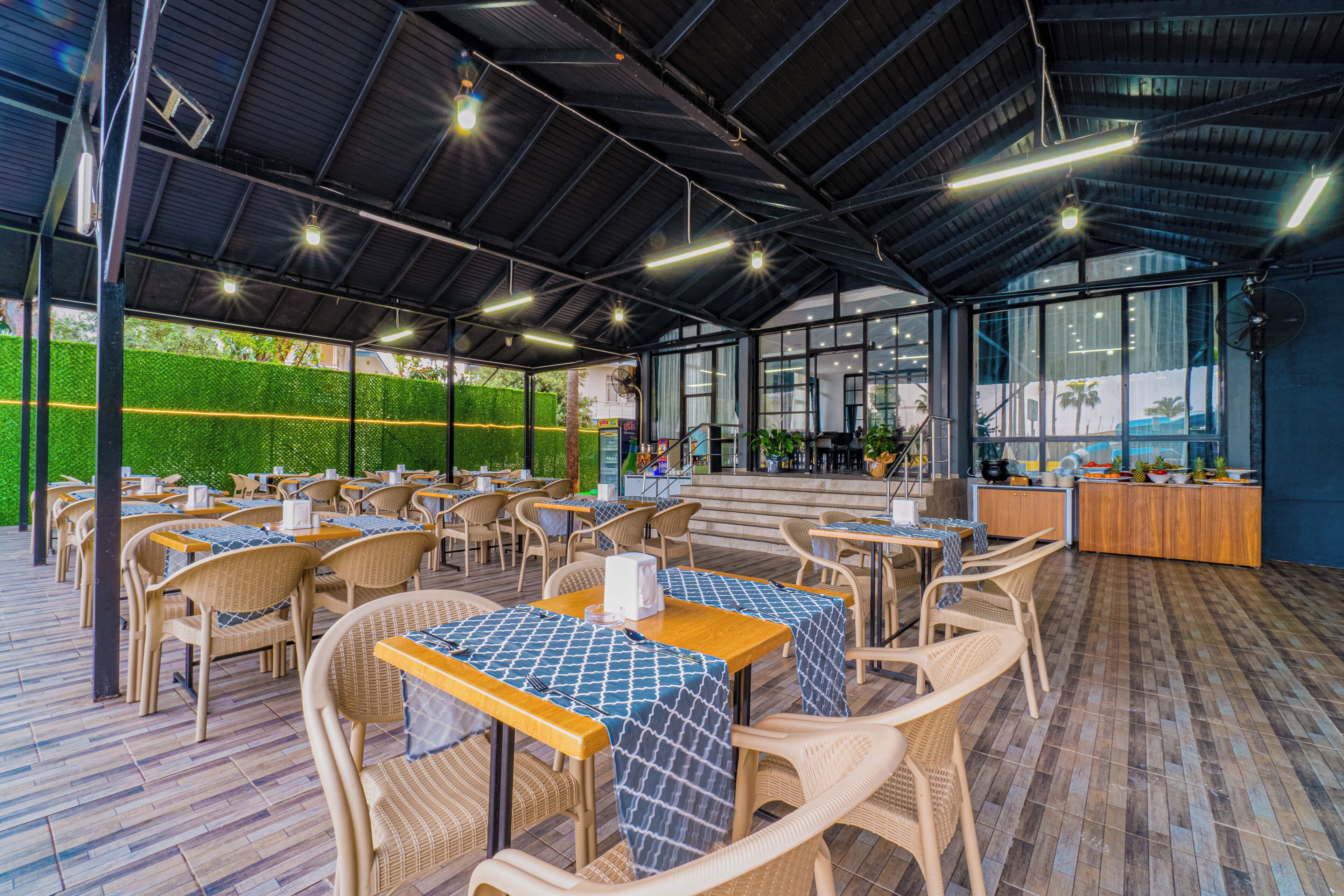 An outdoor cafe with wicker furniture, tables with blue patterned tablecloths, and a view of the outdoors.