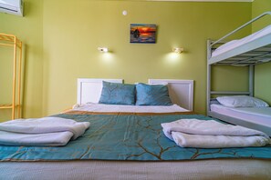 A room with a bunk bed, a bed with a blue and brown patterned bedspread, two pillows, and two towels on the bed. - De Mare Family Hotel (Alanya)