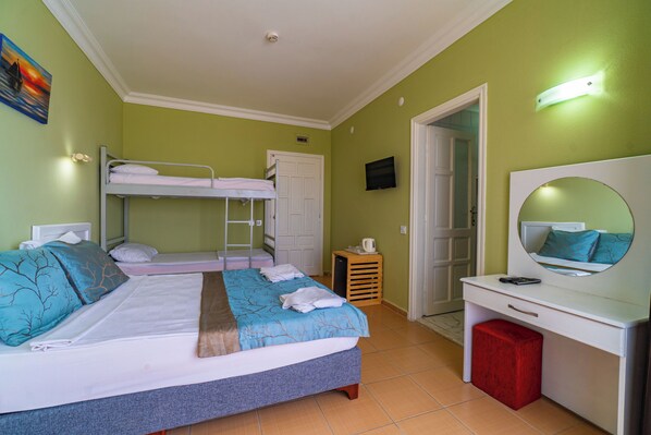 A room with bunk beds, a desk, a mirror, and a television.
