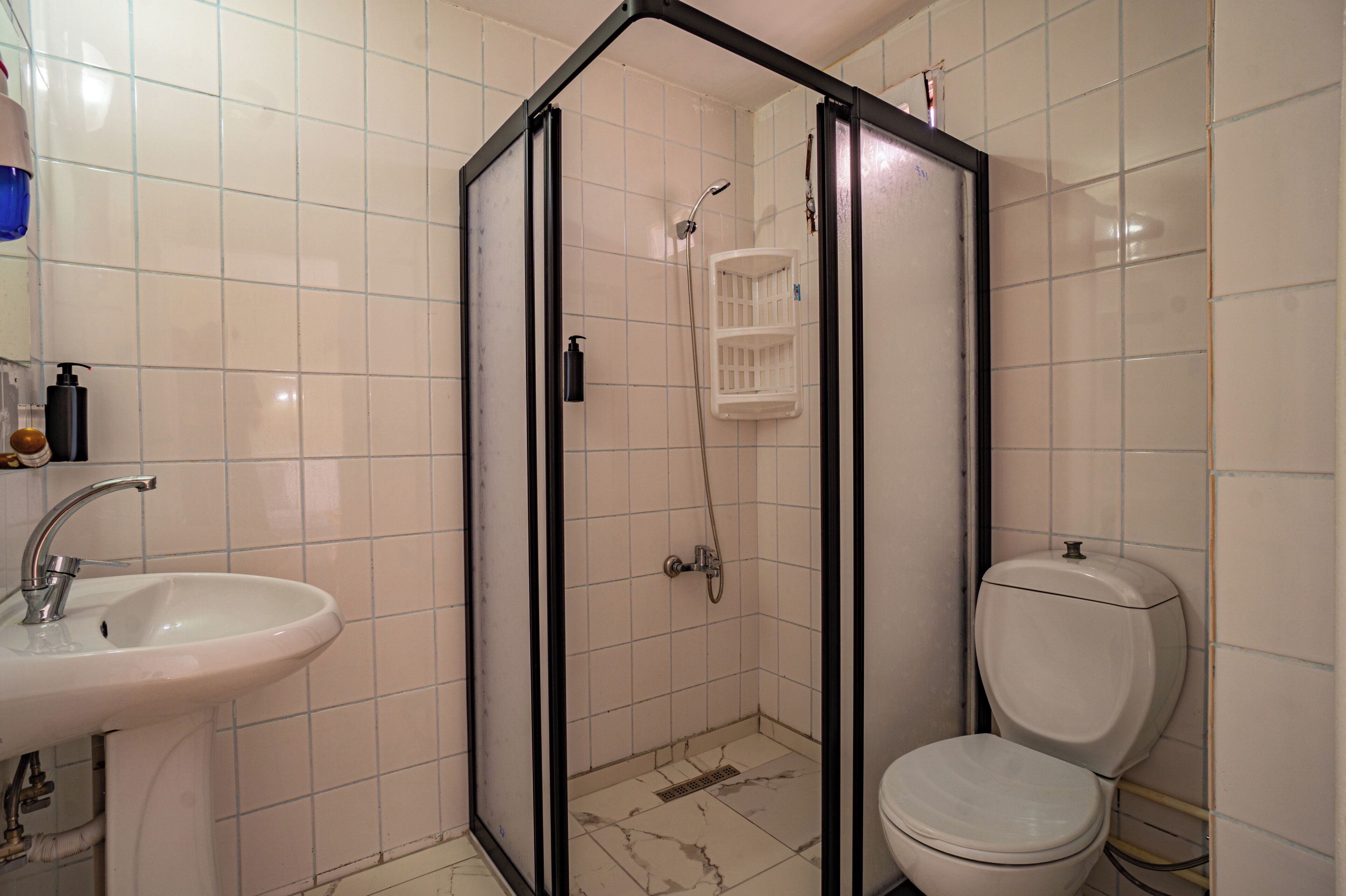 Een badkamer met douchecabine, wastafel en toilet.