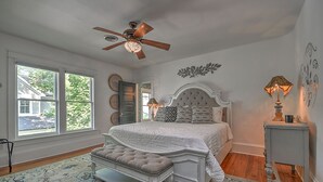 Ein Schlafzimmer mit einem großen Bett, einem Deckenventilator und Blick ins Freie.