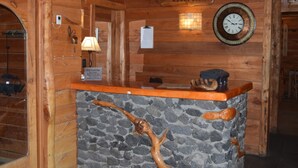 Un mostrador de recepción de madera con un muro de acento de piedra, un reloj y un letrero que dice 'RECEPTION'.