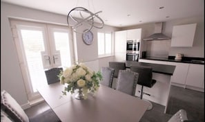 Enjoy meals in this well-lit kitchen and dining area, featuring a stove, oven, and range hood.