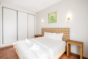 A hotel room with a bed, a large window, a painting, and two wall-mounted lights. - #099 T1 Caliços by Home Holidays (Albufeira)