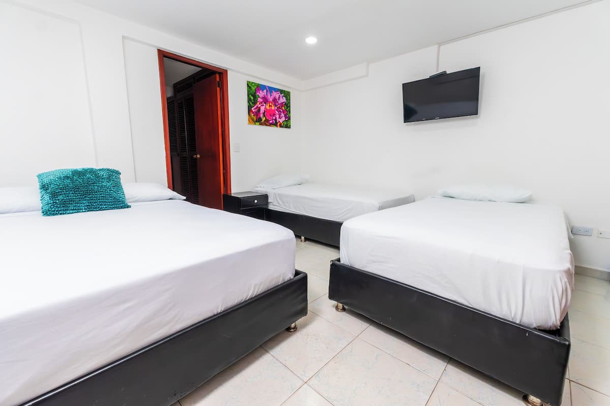 Une chambre d’hôtel avec deux lits, une télévision et une porte donnant sur une autre pièce.