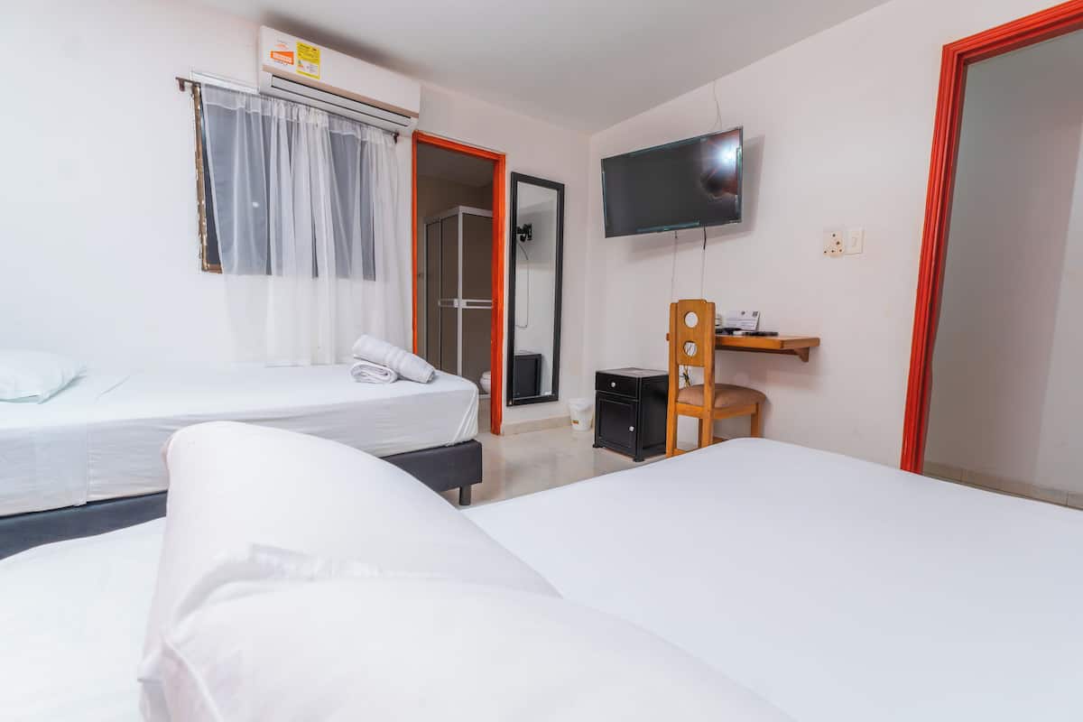Une chambre d’hôtel avec deux lits, une télévision, une petite table et un espace douche.