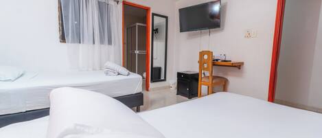 Une chambre d’hôtel avec deux lits, une télévision, une petite table et un espace douche.