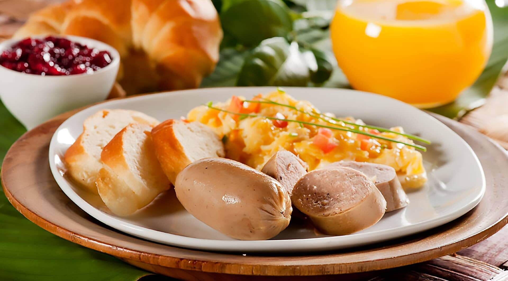 Une assiette avec du pain, des saucisses et une portion de purée de pommes de terre.