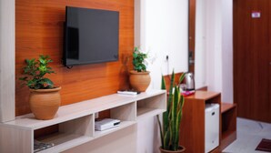 A modern room with a flat-screen TV mounted on a wooden wall, a wooden desk with a computer, and two potted plants. - Hotel Sagar Residency- Best Mountain View Hotel In Palampur (Palampur)