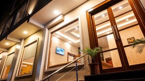 A hotel lobby with a staircase, large windows, and a potted plant. - Hotel Sagar Residency- Best Mountain View Hotel In Palampur (Palampur)