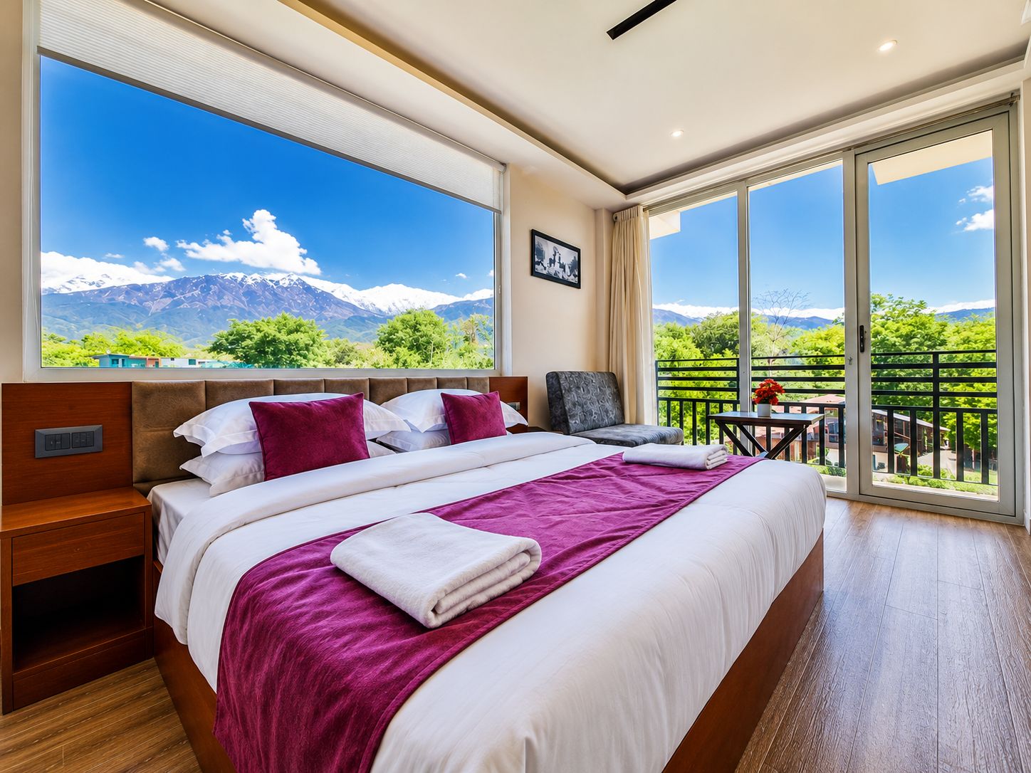 Habitación de hotel con una cama grande, un escritorio y vistas a las montañas a través de la ventana.