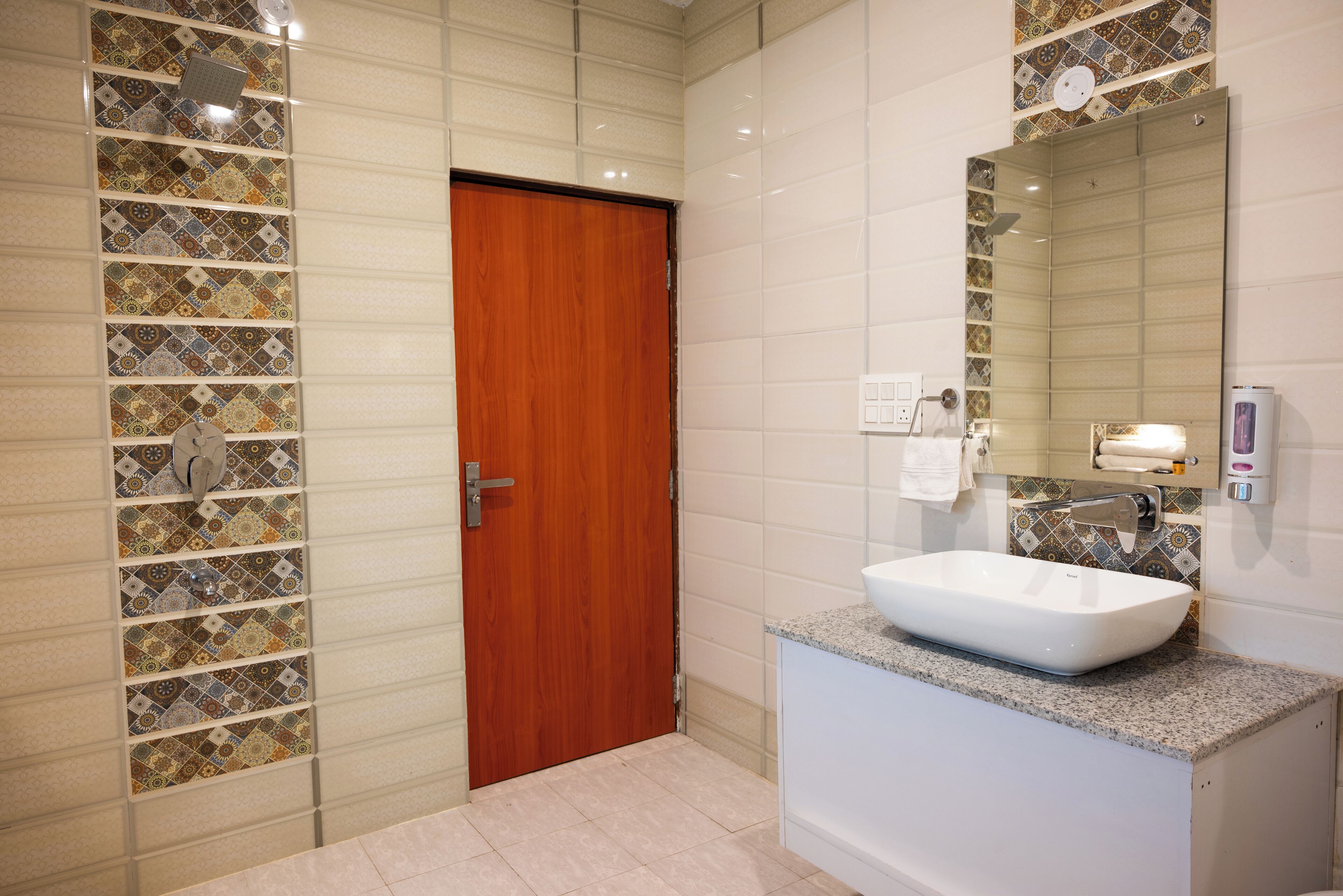 Ein Badezimmer mit Holztür, weißem Waschbecken und gefliestem Spritzschutz.
