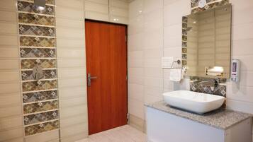 Ein Badezimmer mit Holztür, weißem Waschbecken und gefliestem Spritzschutz.