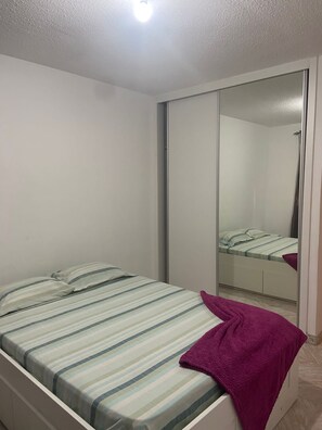 A bedroom with a bed, a mirror, and a wardrobe.