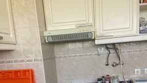 Een keuken met witte kasten, een zwart aanrecht en een witte kookplaat.