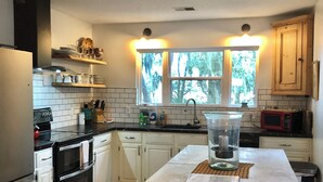 Une cuisine moderne avec des meubles blancs, un îlot central et un ventilateur de plafond.