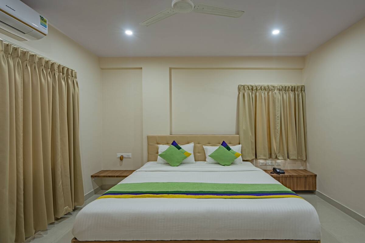 A hotel room with a bed, nightstands, a telephone, and a ceiling fan.