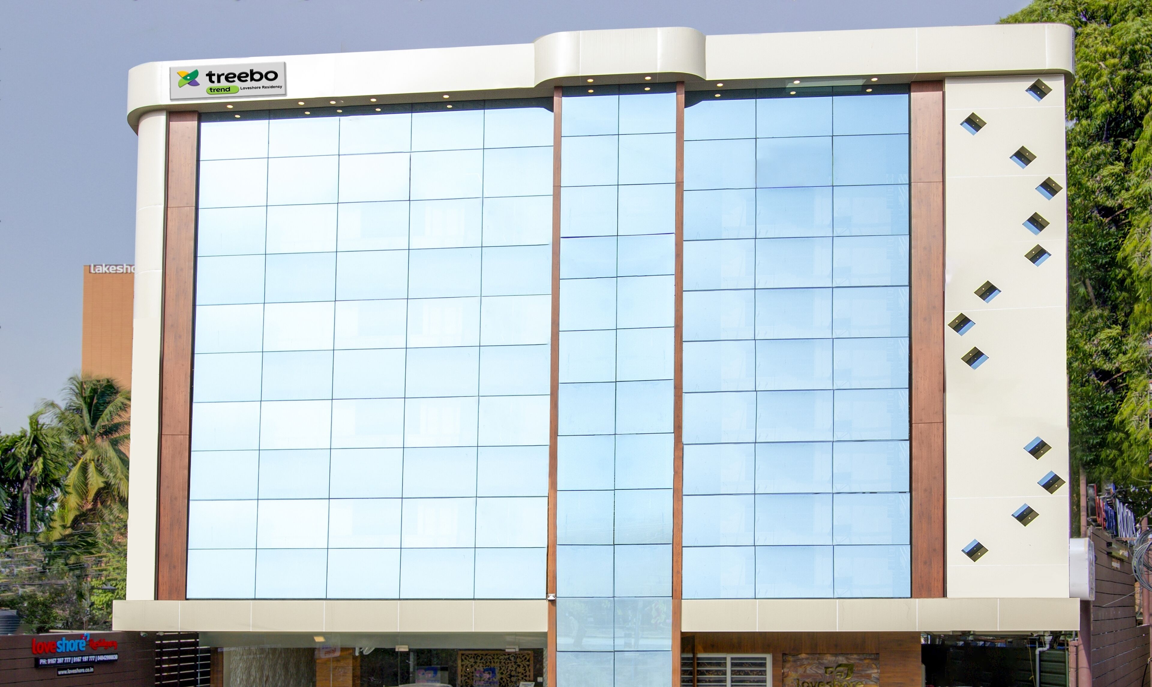 Un bâtiment moderne doté d’une façade en verre, d’un logo bien visible sur le dessus et d’une enseigne indiquant « Love Shore Residencies ».