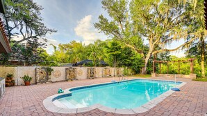 A rectangular swimming pool with a brick deck, surrounded by trees and a stone wall. - Spacious Tampa Vacation Rental w/ Pool & Dock (Tampa)
