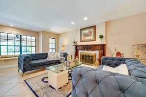 A spacious living room with a large window, a fireplace, and a modern sofa set. - Spacious Tampa Vacation Rental w/ Pool & Dock (Tampa)