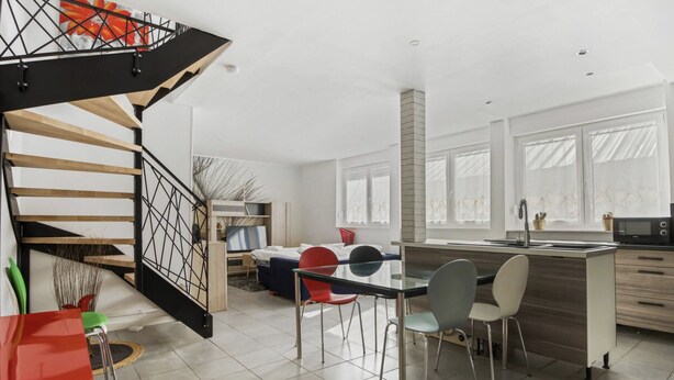 Une cuisine moderne avec un coin repas, un escalier et une vue sur l’extérieur.