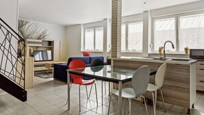 Une cuisine moderne avec un coin repas, de grandes fenêtres et un escalier.