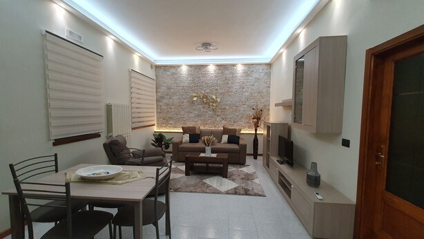A compact living space with a dining area, a sofa, a TV, and a stone accent wall.