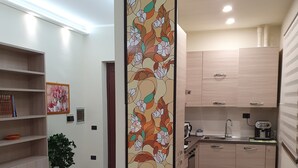 A modern kitchen with wooden cabinets, a dining table with chairs, and a decorative panel with floral patterns.