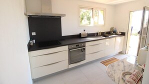 A modern kitchen with a black countertop, white cabinets, a built-in oven, and a window providing natural light. - Villa 6p sea view all comfort beach accessible on foot! (Grosseto-Prugna)