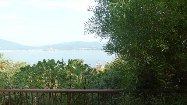 A balcony with a white chair and a table with a polka dot tablecloth, overlooking a body of water and greenery. - Villa 6p sea view all comfort beach accessible on foot! (Grosseto-Prugna)