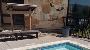 Une piscine rectangulaire aux carreaux bleus, avec un mur de pierre en arrière-plan.