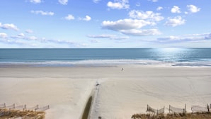 Una extensa playa de arena con cielo despejado y mar.