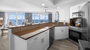 Una cocina moderna con gabinetes blancos, encimera de granito y electrodomésticos de acero inoxidable.