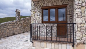Un edificio de piedra con puerta de madera y barandal de metal negro.