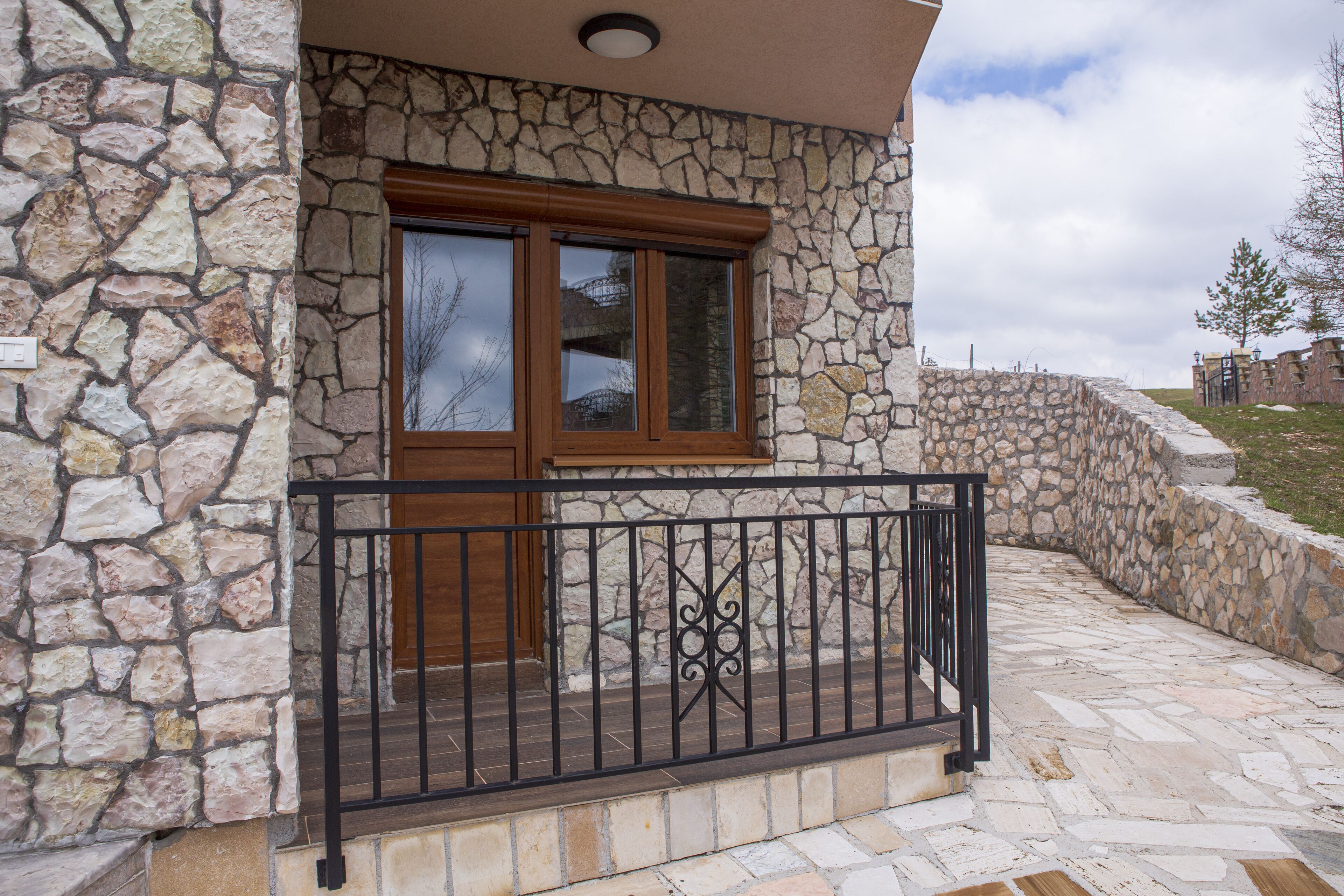 A stone building with a wooden door and a black metal railing.