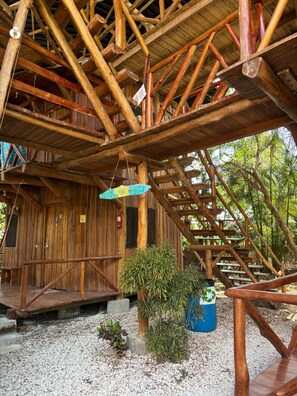 A rustic wooden structure with a wooden staircase and a hanging light fixture. - Don Jons Lodge -Surf & Yoga (Cóbano)