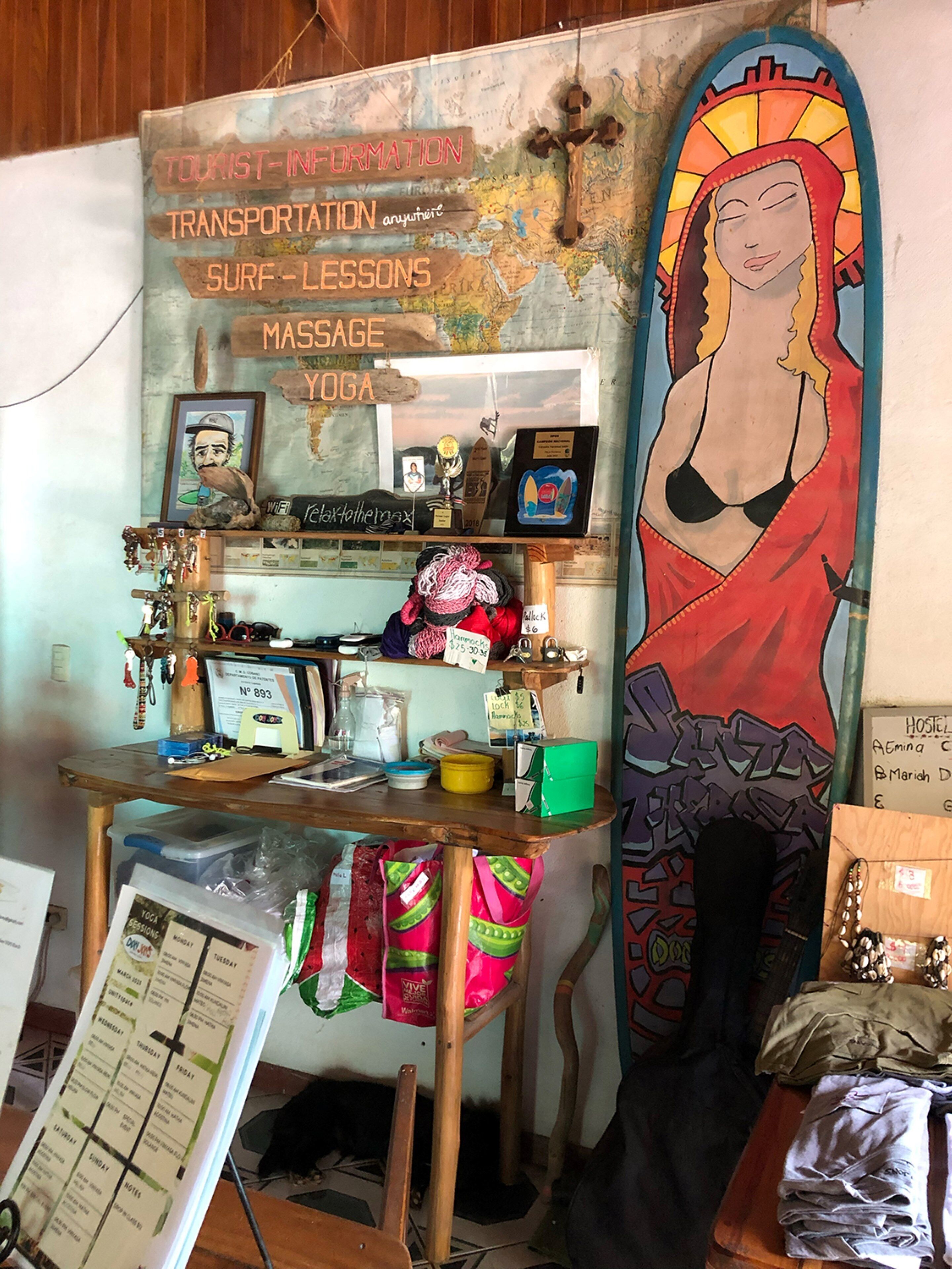 A cluttered room with a surfboard, a map, and various items on shelves.