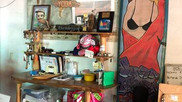 A cluttered room with a surfboard, a map, and various items on shelves.