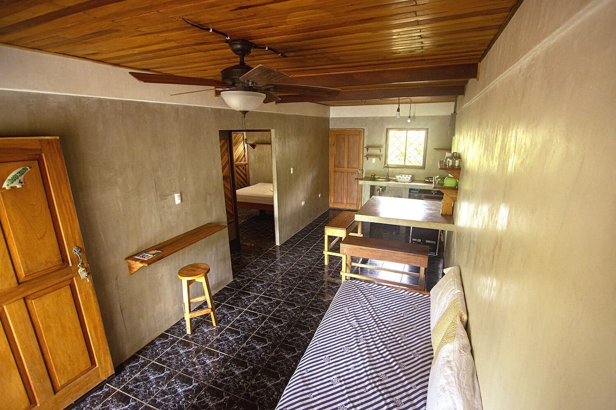 Una cocina compacta con techo de madera, un banco empotrado y un taburete pequeño.