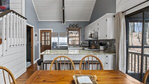 A kitchen with white cabinets, a stainless steel refrigerator, and a large window. - Beautiful Views, Arcade, Shuffleboard, Pinball, 4BR 3BA - 3 King Beds (Big Canoe)