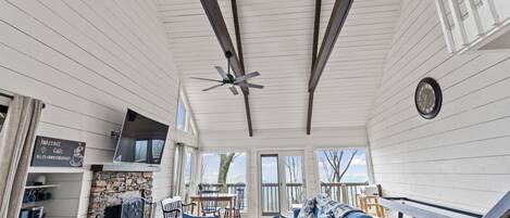 A spacious deck with a blue sofa, a stone fireplace, and a dining area.