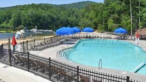 A swimming pool with a fenced deck, lounge chairs, and blue umbrellas. - Beautiful Views, Arcade, Shuffleboard, Pinball, 4BR 3BA - 3 King Beds (Big Canoe)