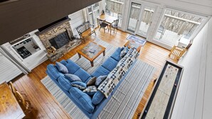 A spacious living room with a blue sofa, wooden coffee table, and a fireplace. - Beautiful Views, Arcade, Shuffleboard, Pinball, 4BR 3BA - 3 King Beds (Big Canoe)