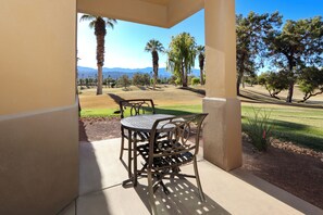 A patio with a table and chairs, overlooking a golf course with palm trees and a clear sky. - COACHELLA Marriott's Desert Springs Villas Kitchenette, access to resort (Palm Desert)