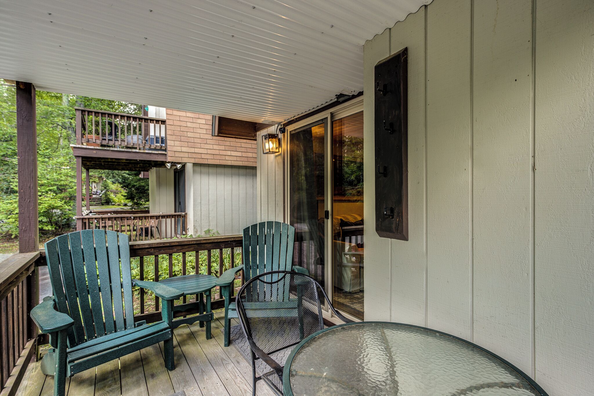 En inglasad veranda med två Adirondack-stolar och ett bord i glas.