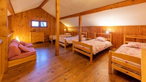 Une cabane en bois avec quatre lits, une commode et une fenêtre.