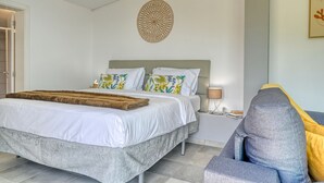 Ein Schlafzimmer mit einem Bett, einem Nachttisch, einer Lampe und einem Sessel.