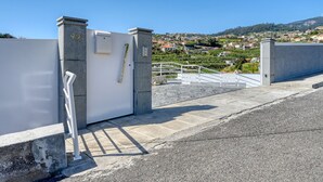 Ein begrenzter Eingangsbereich mit einer weißen Tür, einer Steinsäule mit der Nummer 92 und Blick auf eine an einem Hügel liegende Stadt mit Häusern.