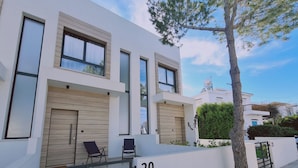 A modern two-story building with large windows, a wooden door, and a gated entrance. - STAY Anemone 20 (Protaras)