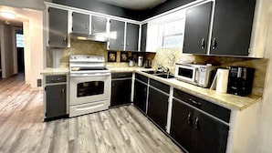 A compact kitchen with a built-in oven, microwave, and sink. - Beach Break House by the Surf (Daytona Beach)